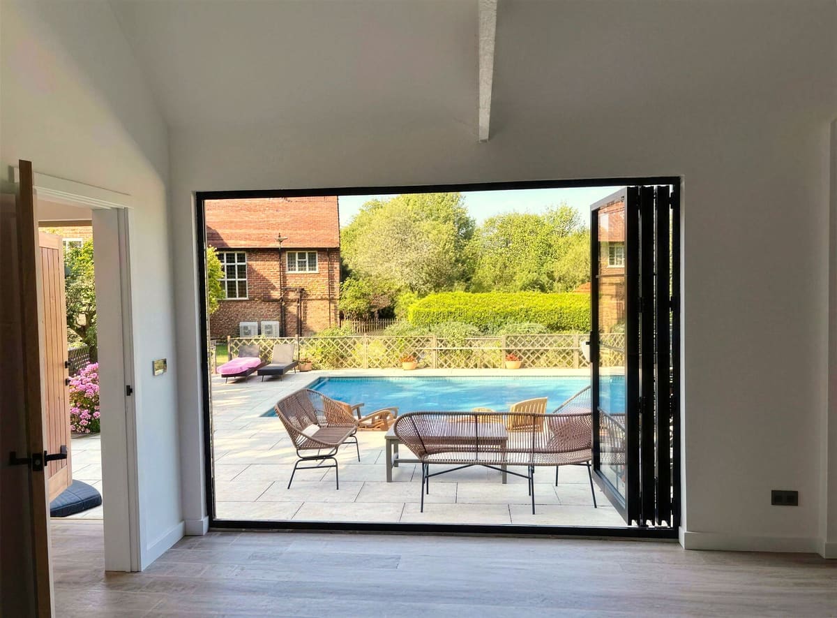 Crittall-style bi-fold doors opening onto the pool