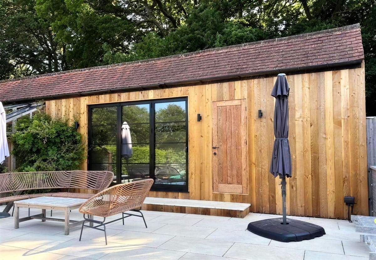 Barn conversion exterior with patio furniture and parasol