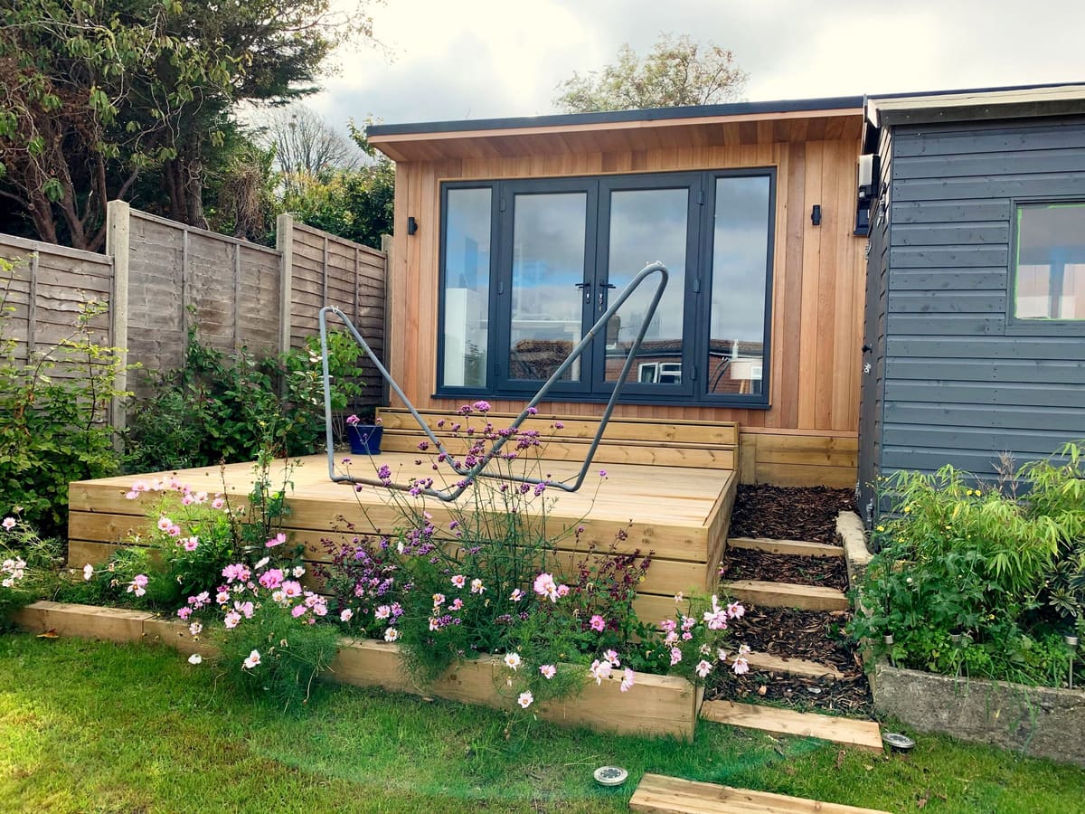 Cedar garden room on a raised timber deck with steps and a flower bed in front
