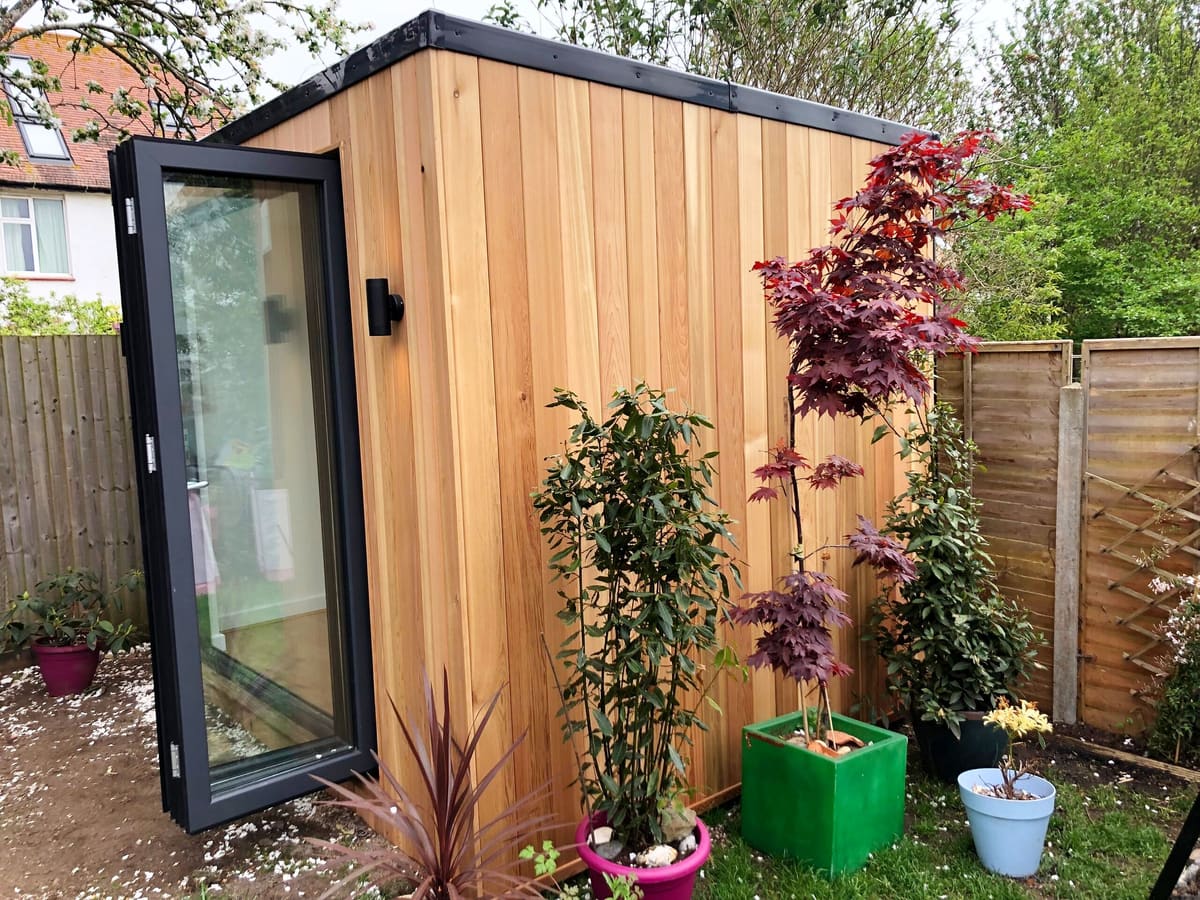 Cedar garden room with bi-fold doors, a red acer and planting