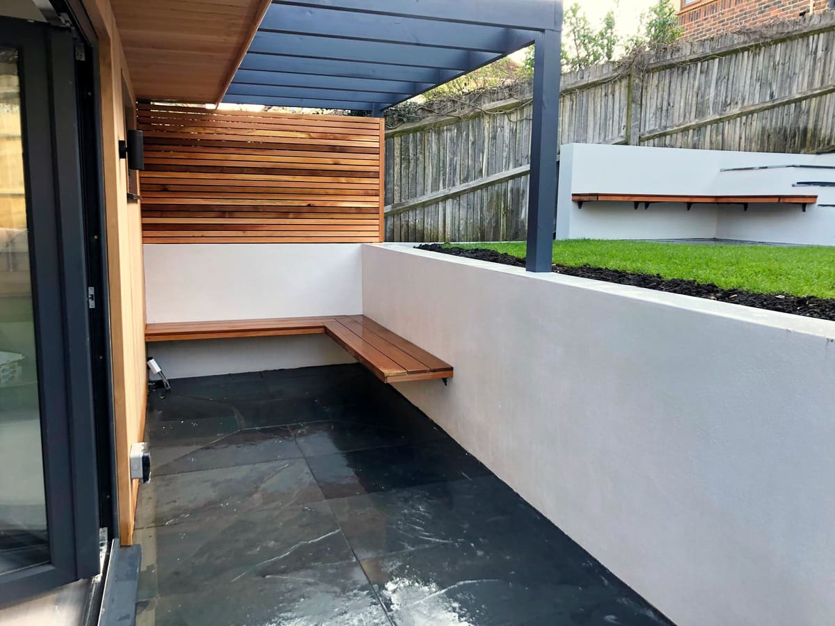 Rendered walls, floating bench and slate paving under a pergola